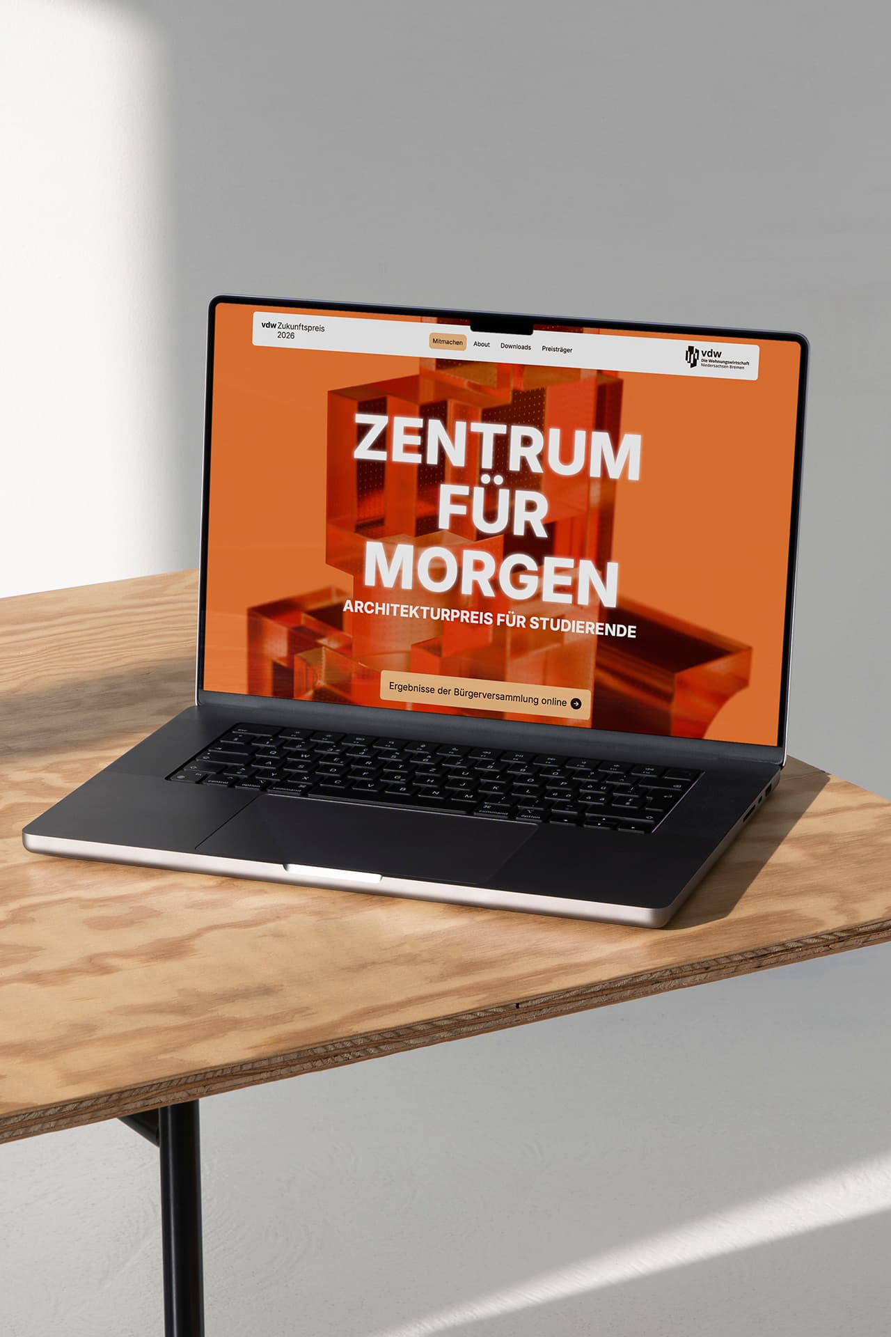 Ein MacBook steht auf einem Holztisch. Auf dem Bildschirm sieht man die Startseite der Internetseite des vdw Zukunfstpreises.