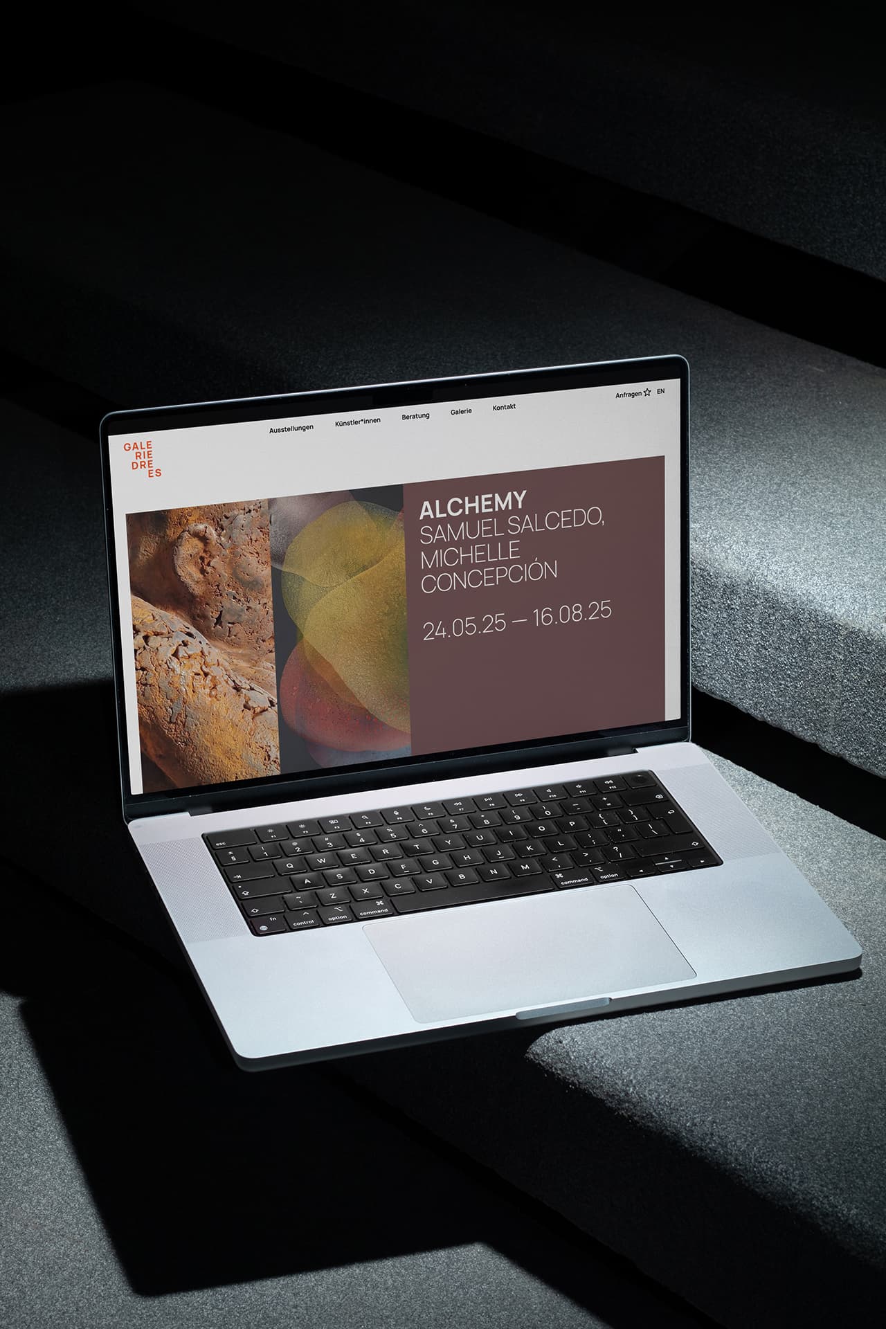 Ein MacBook steht auf einer Treppenstufe aus Stein. Auf dem Bildschirm sieht man die Startseite der Webseite der Galerie Drees.